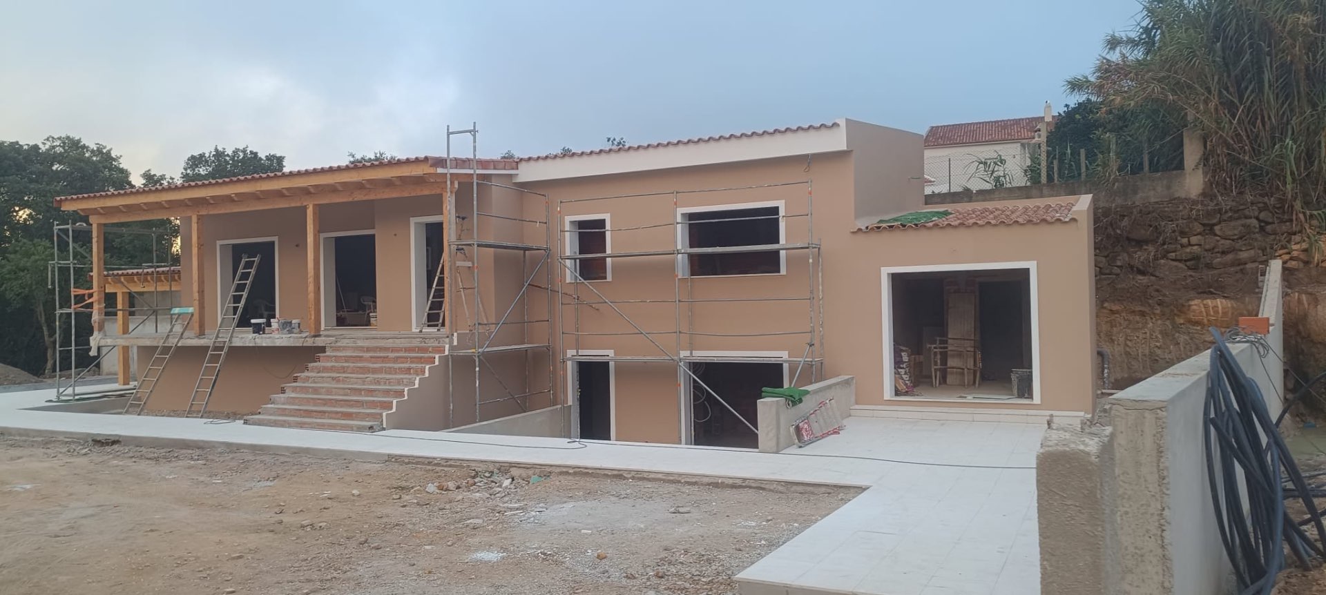 Fachada de moradia com capoto aplicado e acabamento em tom areia, com andaimes ainda montados